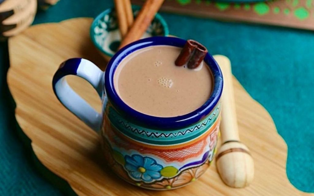 Hot chocolate, a typical Mexican drink served in a traditional Mexican clay cup accompanied with cinnamon that provides a unique flavor
