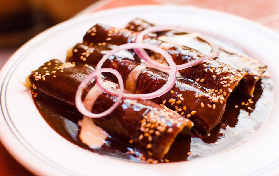 Mole enchiladas covered with chili peppers, chocolate and spices sauce
